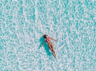 Woman floating on her back on top of Hawaiian blue ocean water