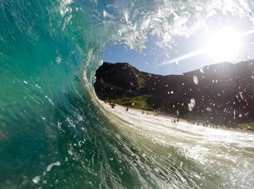 Close-up photo of a large wave near a sunny beach